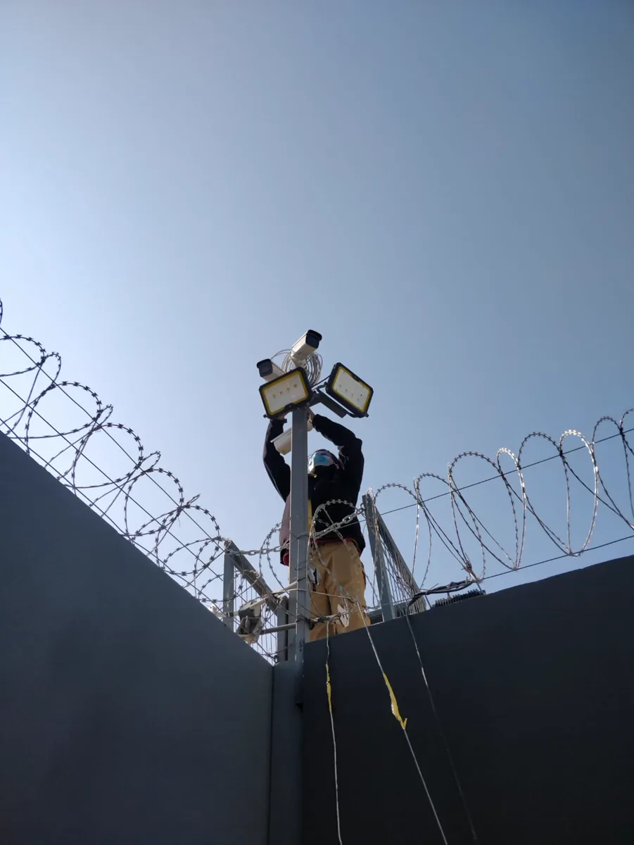 Técnico sobre una escalera trabajando en una instalación exterior de vigilancia